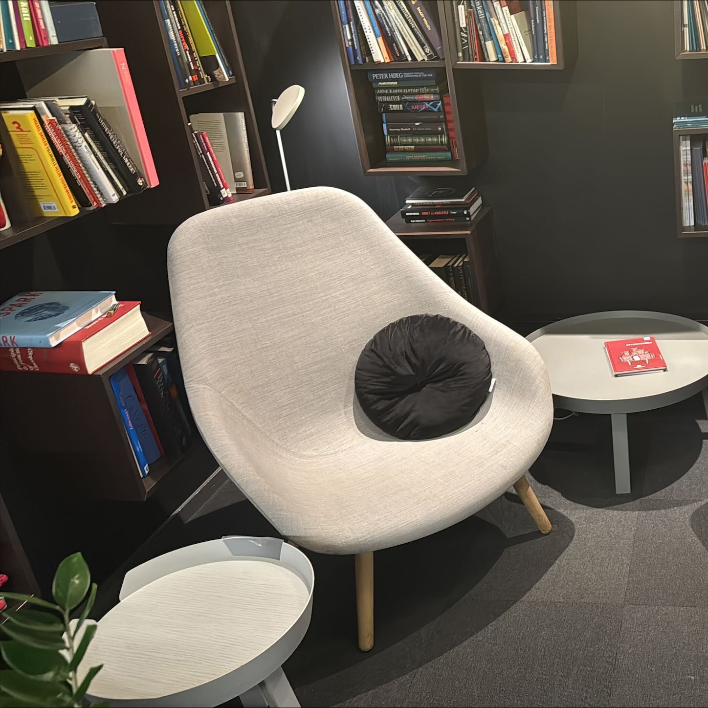 Kontorsbibliotek med ljusa textilfåtöljer och bokhyllor