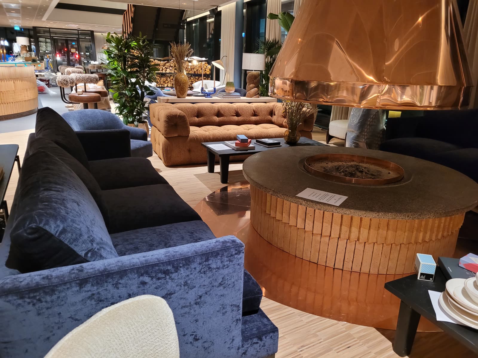 Hotellobby med öppen spis i koppar, blå velurfåtöljer och sammetssoffa