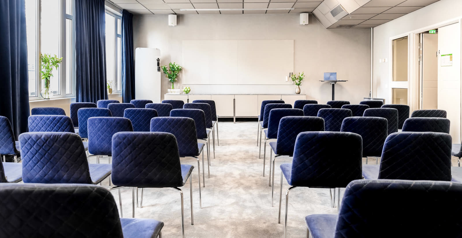Konferensrum med blå velurstolar och matta